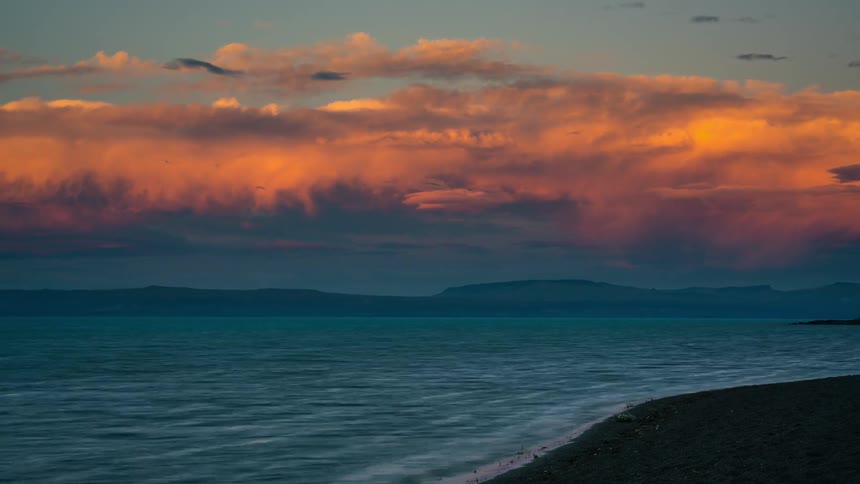 Landscape of a beach with orange clouds and the day getting dark