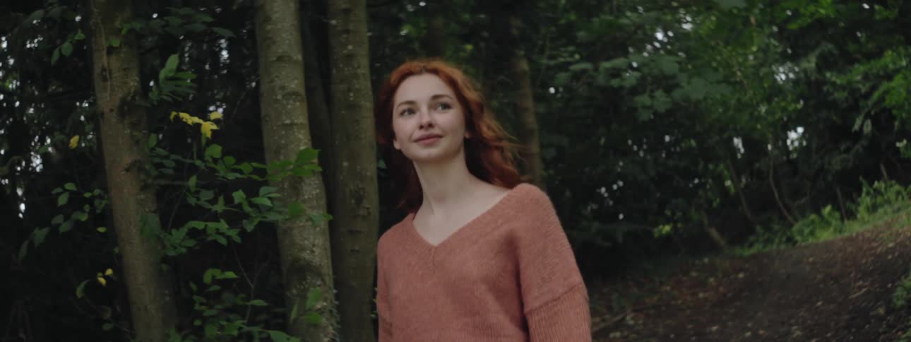 A woman smiles as she walks along a path lined with trees