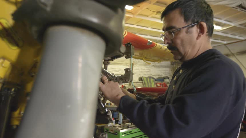 Spectacled man working on an airplane engine indoors