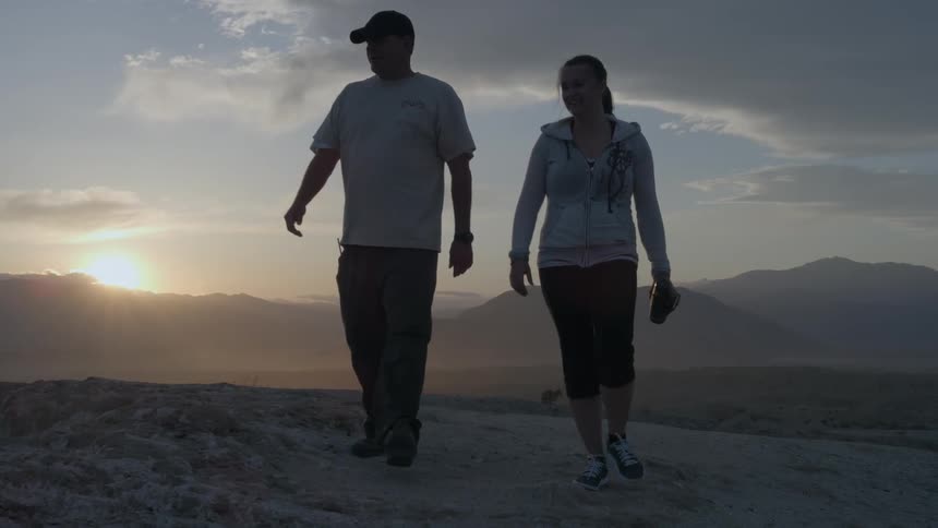 Couple walking along the open wilderness as the sun sets behind them