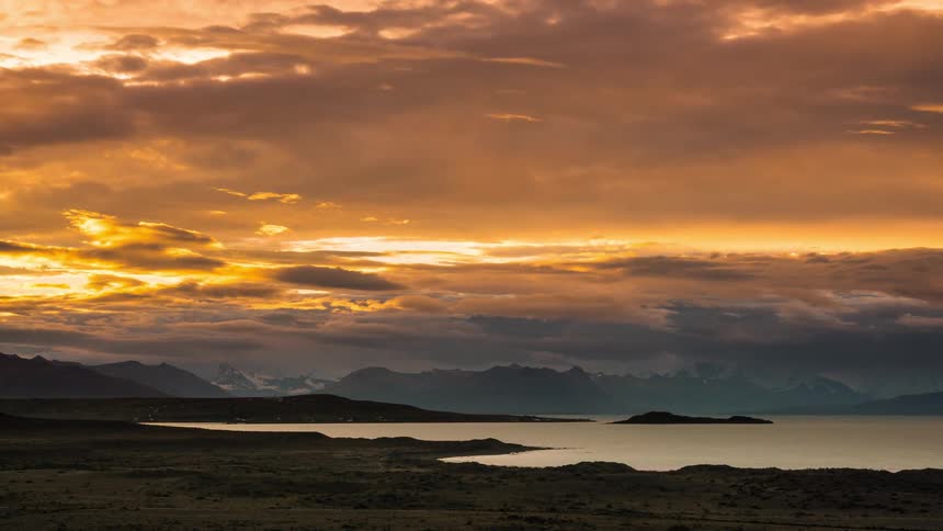 Clouds pass over a mountainous landscape located at a coastline