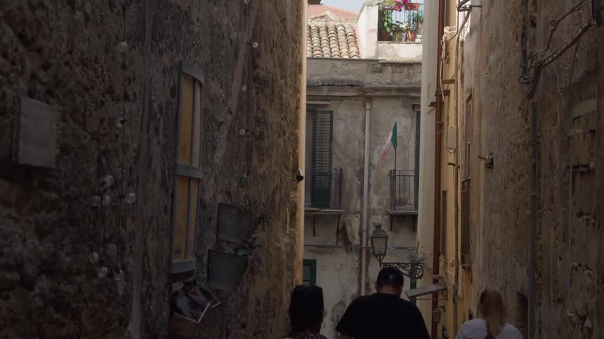People walking in an alley lined with urban and classic walls