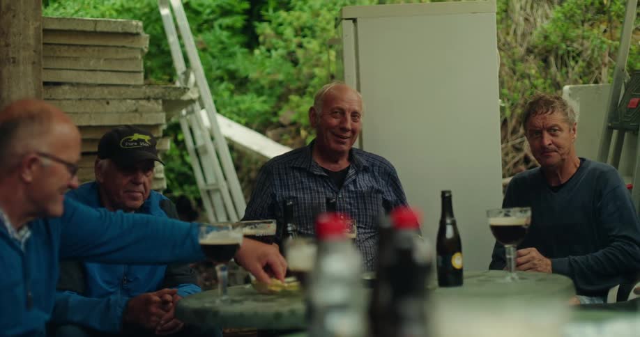 A group of men sit around having drinks