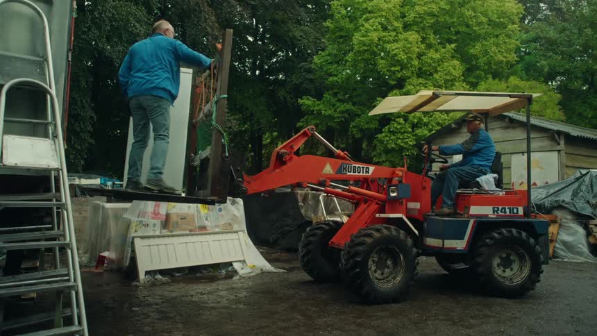 A mover drives a large forklift type vehicle to get a freezer into a trailer truck