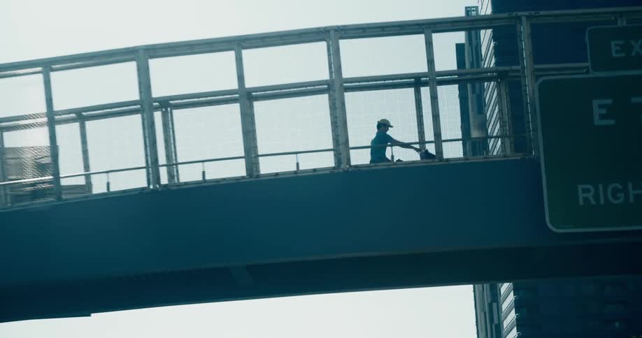 Elevated walkway with a person pushing a baby stroller in a metropolis during the day