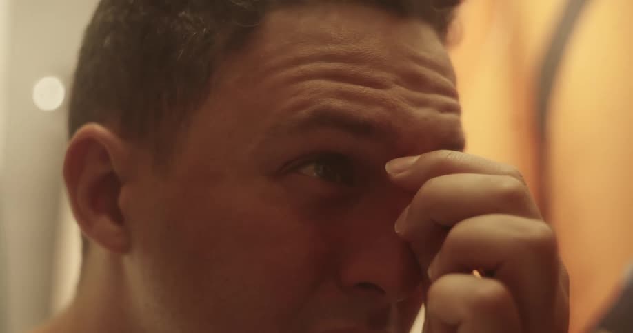 A man is checking the skin on his face in a mirror