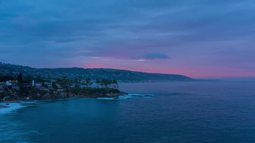 Clouds and waves move over and next to a city and suburban area on a coast