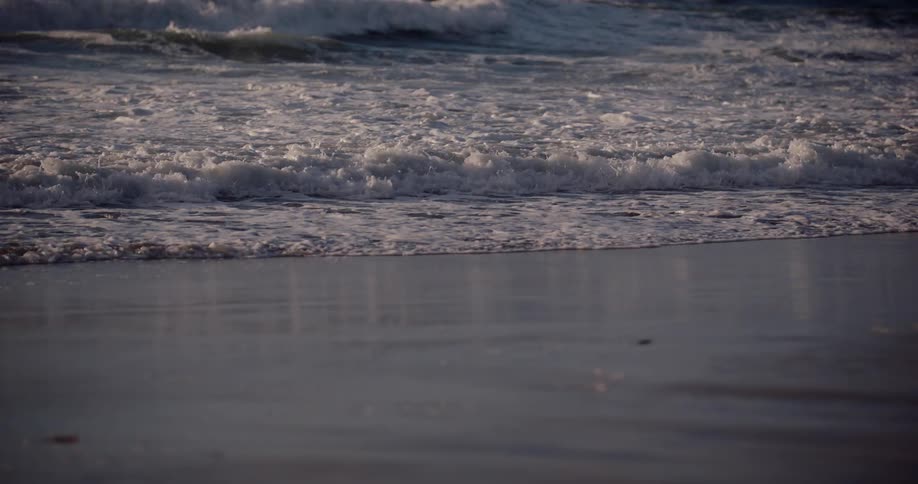 Sea waves rolling onto the shoreline at sunrise
