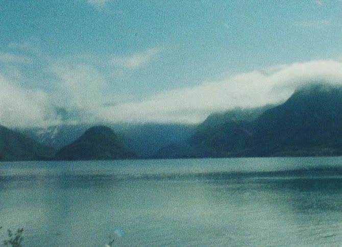A serene lake surrounded by mountains shrouded in mist creating a tranquil and picturesque scene