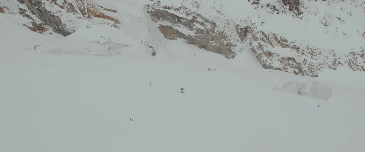 A professional skier quickly moves down a snow covered mountain