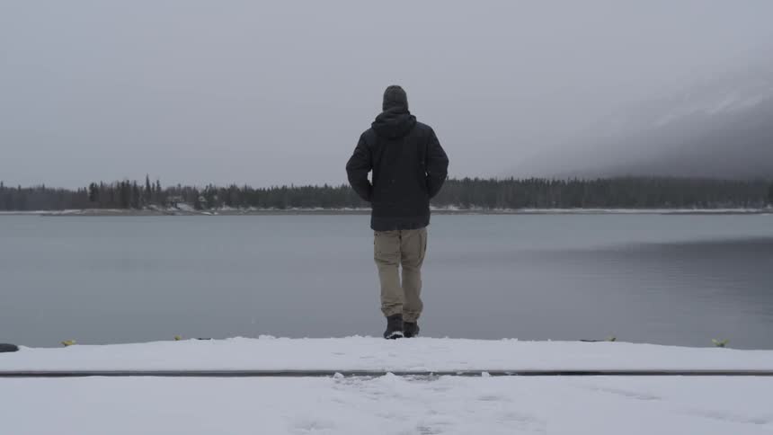 A man walks to the water's edge in the snow