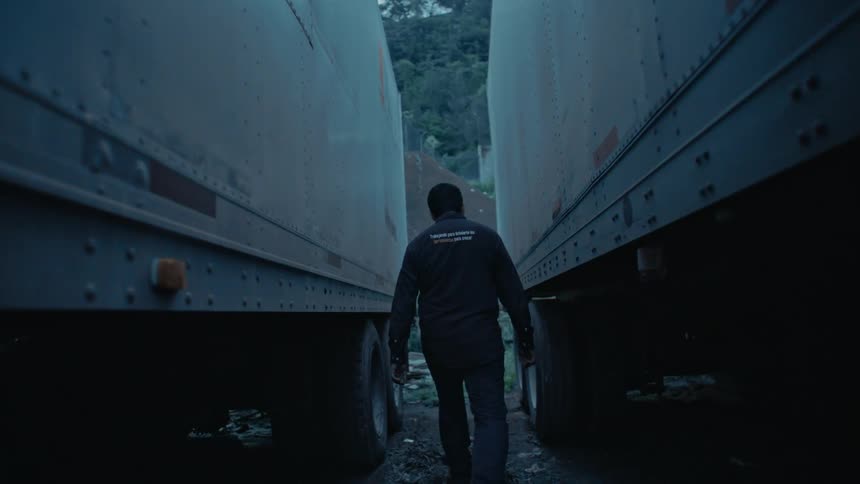 Man with a tool in his hand walking between two trucks