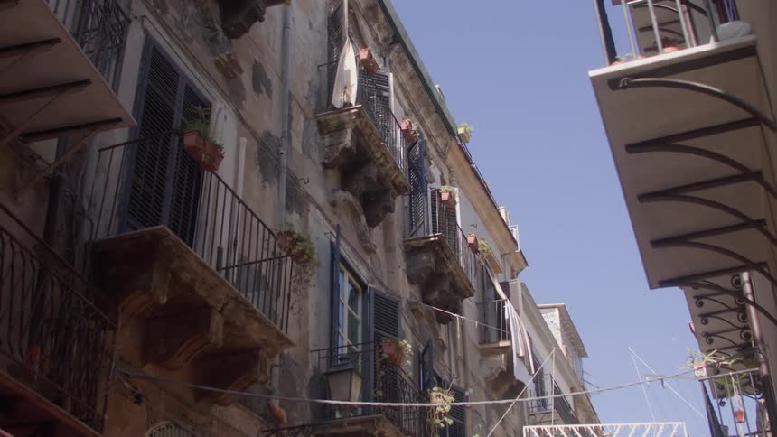 Facades of old buildings with several wrought iron balconies and potted plants