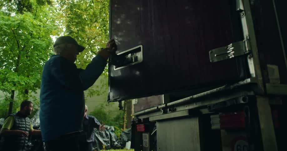A man closes the back doors of a large truck