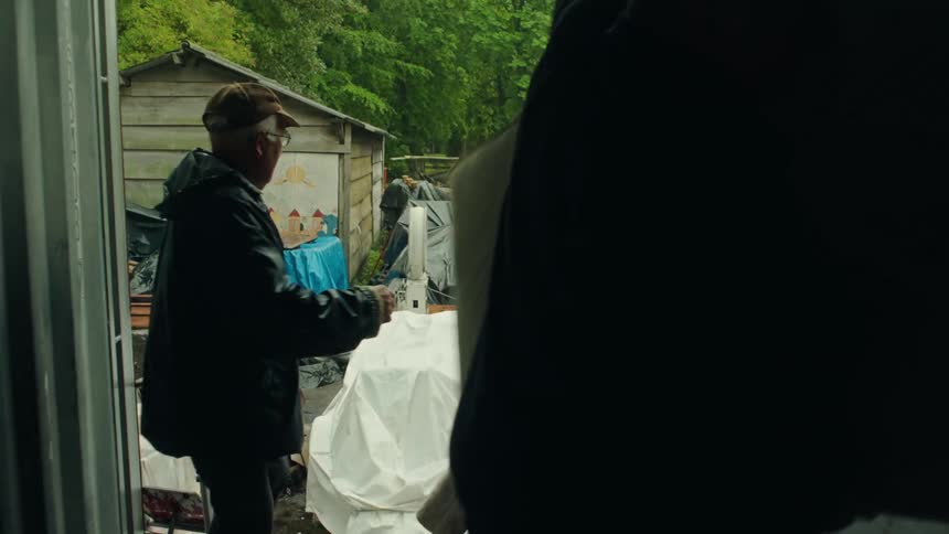 Several people carrying mattresses in their arms and placing them inside a space where there are some men arranging them