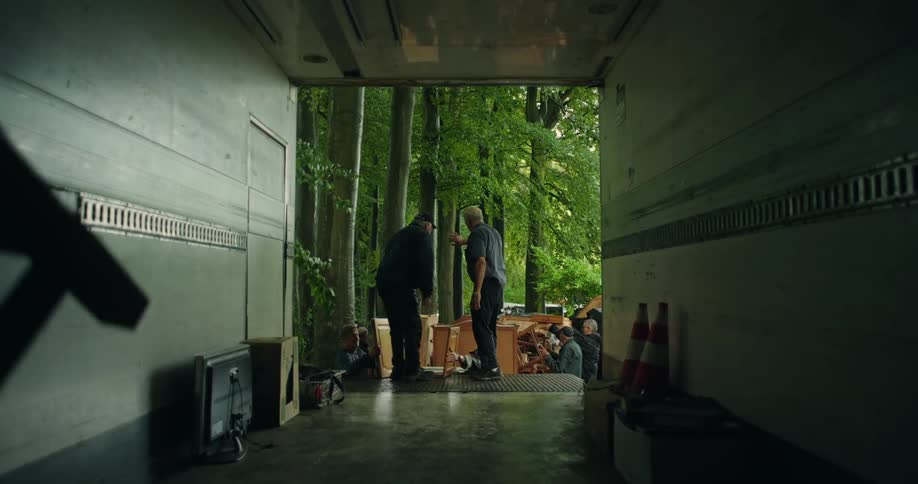 A group of movers unloads items from a large trailer