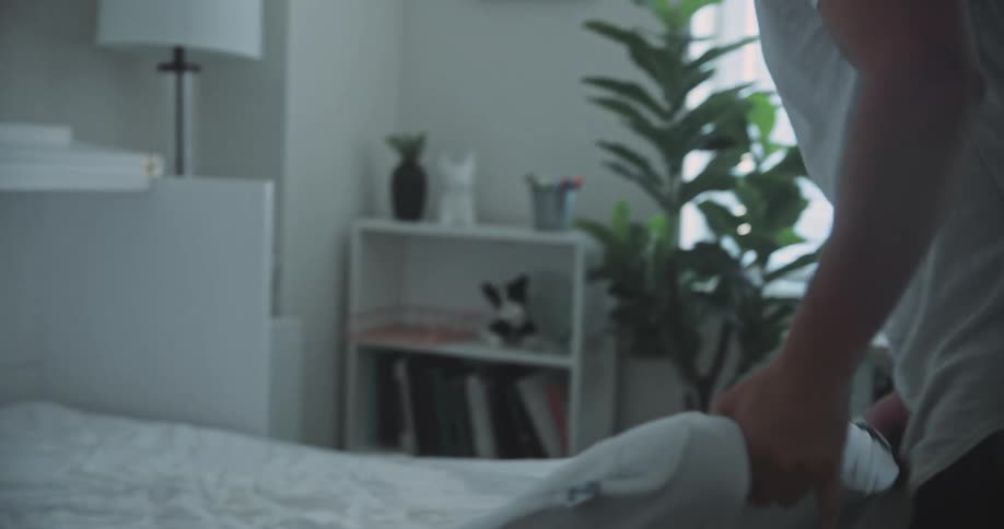 A man tries to get a mattress off of his bed and is annoyed at how difficult it is