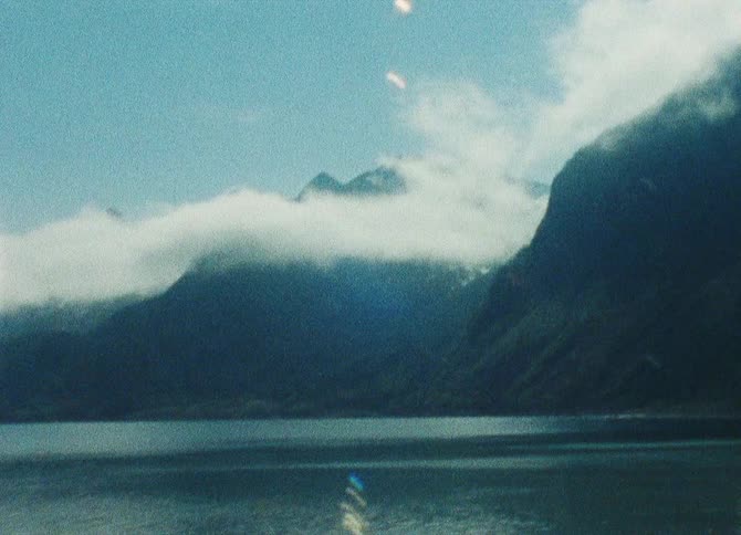A serene mountain landscape with peaks shrouded in mist reflecting on the calm waters of a lake