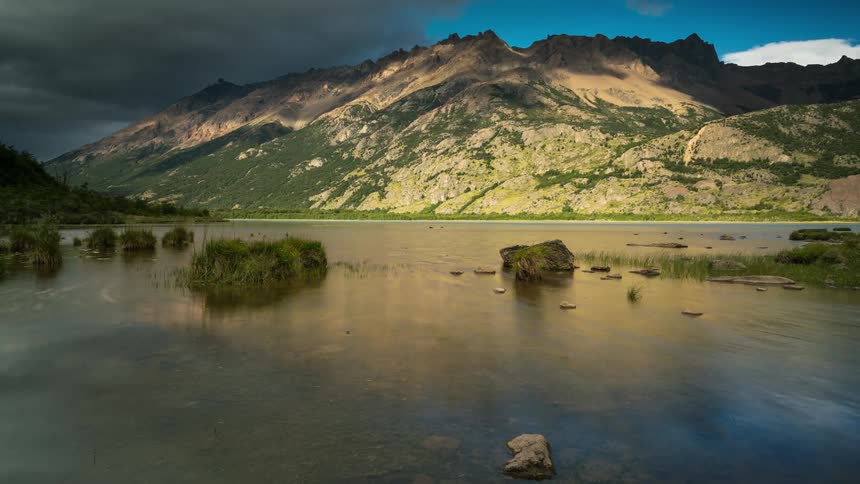 A tranquil lake reflecting the majestic mountains and dramatic cloudscape