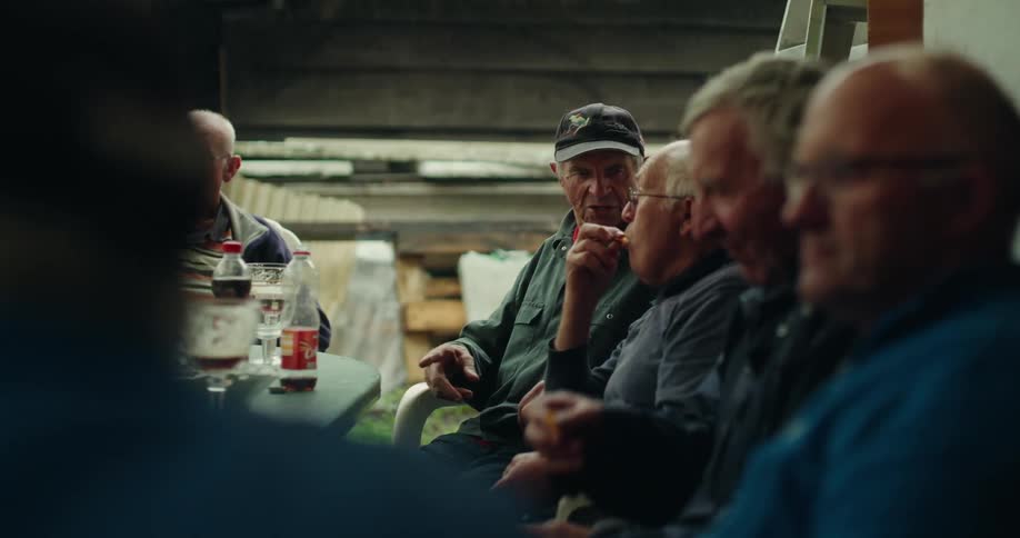 Group of men sitting in an outdoor area talking and eating