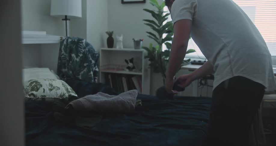 Man removing items from a bed in a bedroom