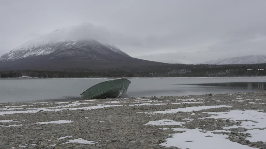 Boat resting on the shore in a cold area with mountains in the distance