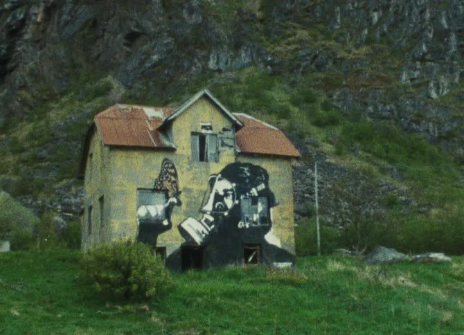 A dilapidated graffiticovered house stands abandoned against a backdrop of rugged mountains blending into the natural landscape