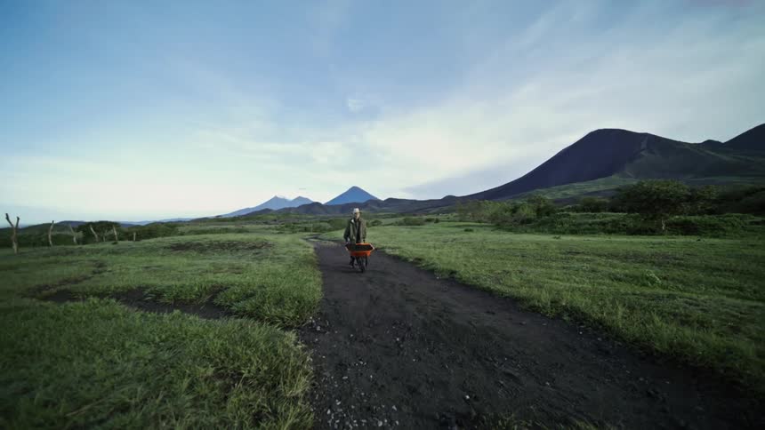 A man is pushing a wheelbarrow down the path