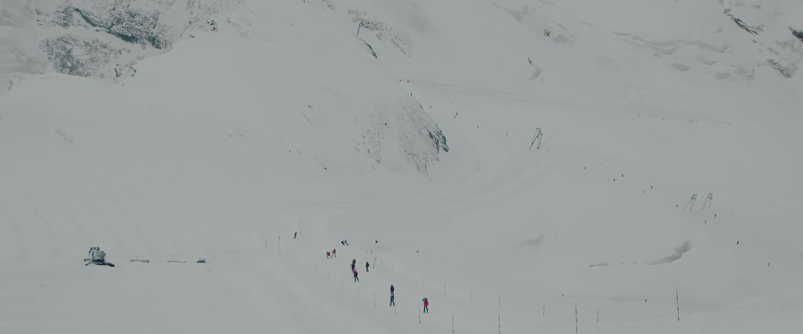 People ski across the snow covered terrain leading toward a mountain slope on a winter day