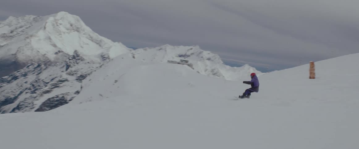 Person snowboarding down a mountain with an epic view in the distance