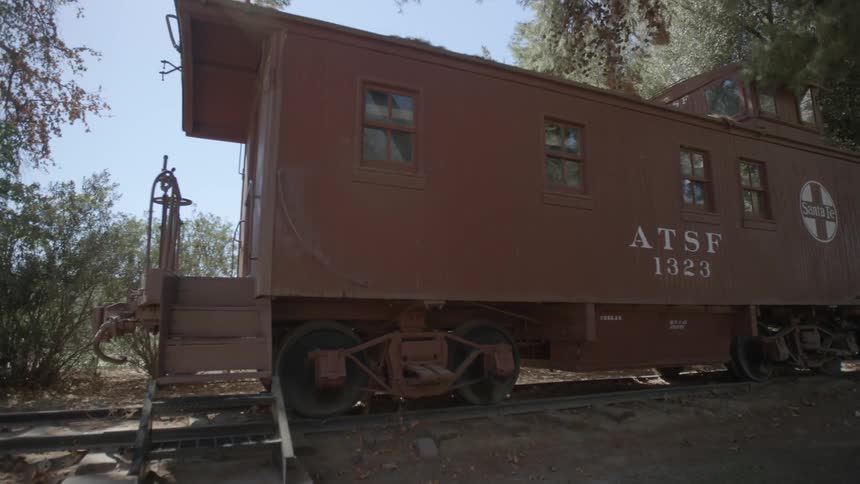 An old train car is sitting on tracks surrounded by trees