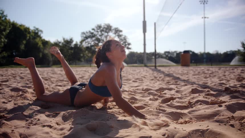 A woman jumps forward reaching for the volleyball