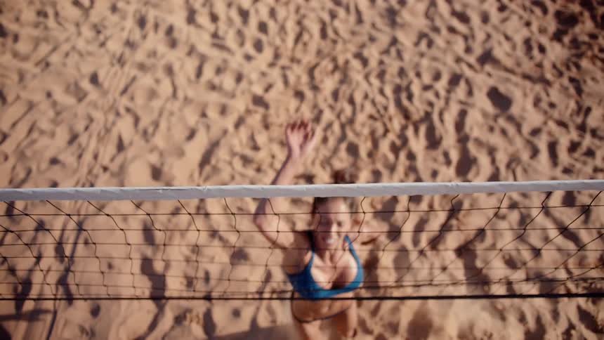 A woman jumps up to hit the volleyball