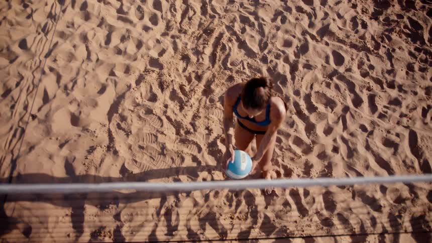 A woman taps the volleyball by the net