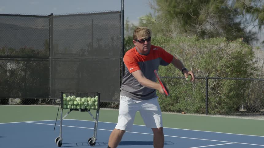 A man hits a tennis ball with his racket