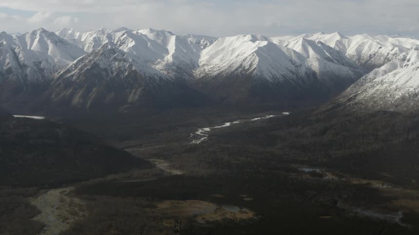Looking down at the wide valley surrounded by snow covered mountains