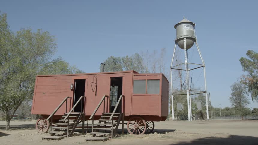 Old building  on wagon wheels with stairs leading in and out on a clear day