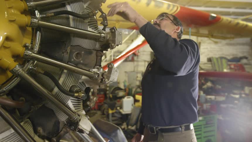 A man inspects the engine of an small airplane