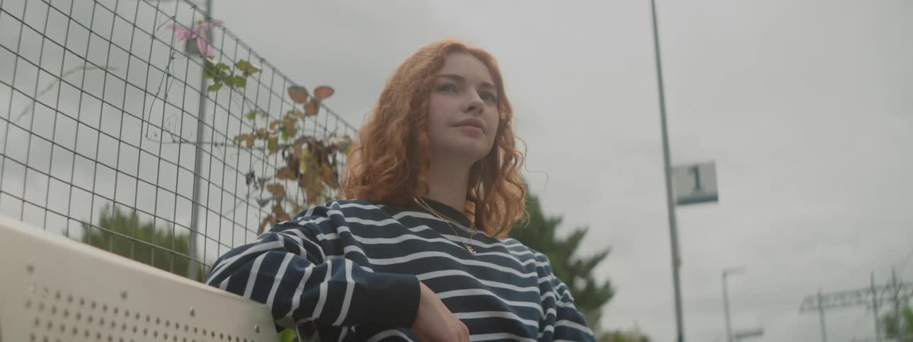 Redhaired woman with red hair sitting in an openair public area