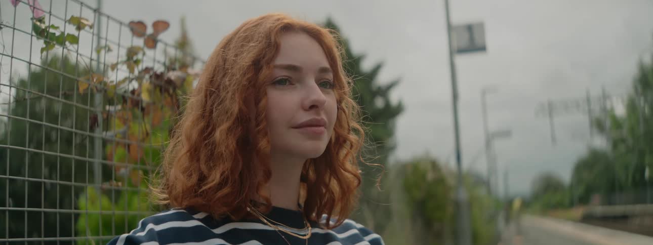 Redheaded woman sitting in an outdoor area on a cloudy day
