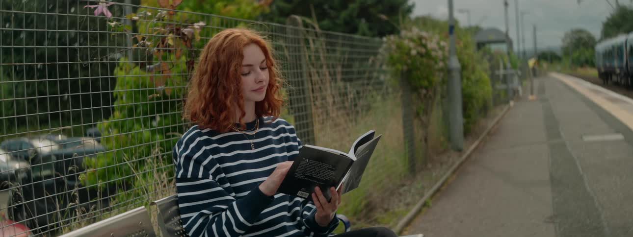 Woman sitting on a bench outdoors reading a book