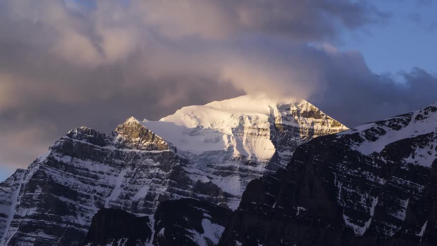 Gray clouds pass over snow dusted mountains on a winter day