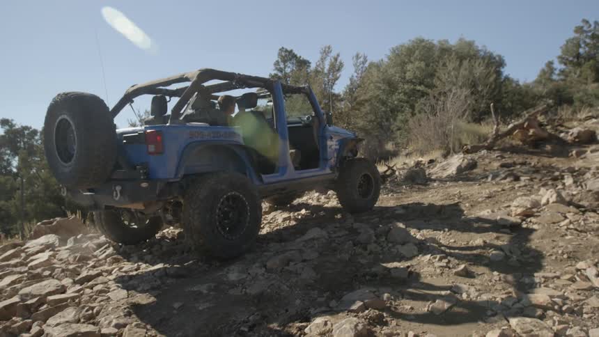 Jeep maneuvering up a rocky incline on a clear day