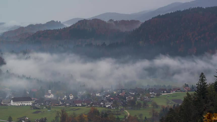 Landscape of mountains and a village in the background with low clouds