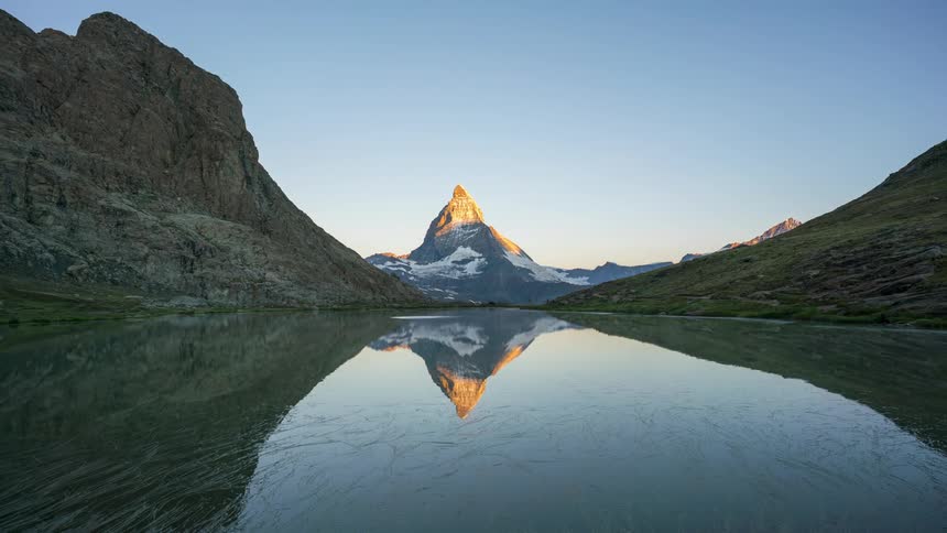 Portrait of a lake reflecting the surrounding mountains on a morning