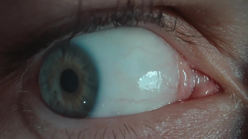 A persons eye with a greenish iris and the eye is moving rapidly left and right