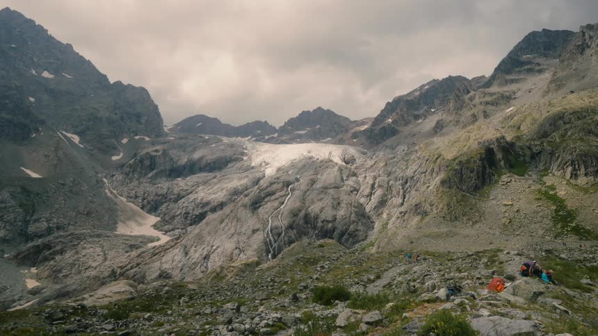 A campsite next to a mountain range with ice pockets on it
