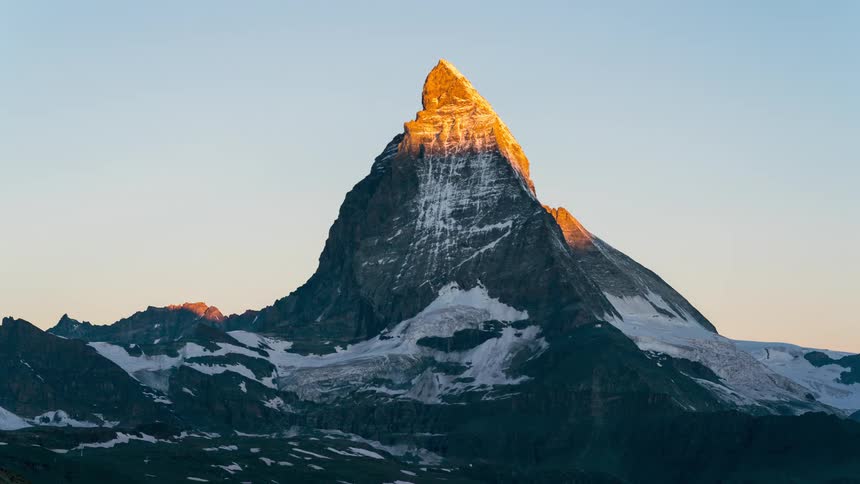 Landscape of a steep mountain cliff with golden sun passing above