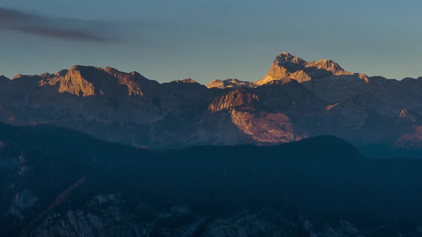 A range of stone mountains on a clear day that is getting dark and getting dark clouds in the sky