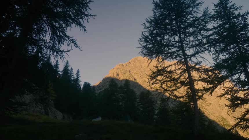 Natural scenery of mountains with conifers and the reflection of the sun at dawn